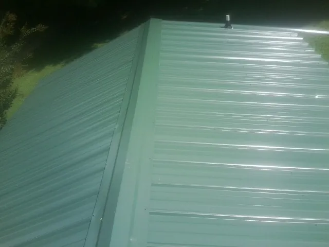 New green metal panels meeting at the ridge of a roof — Flat Roof Repair work by our crew in Kintnersville