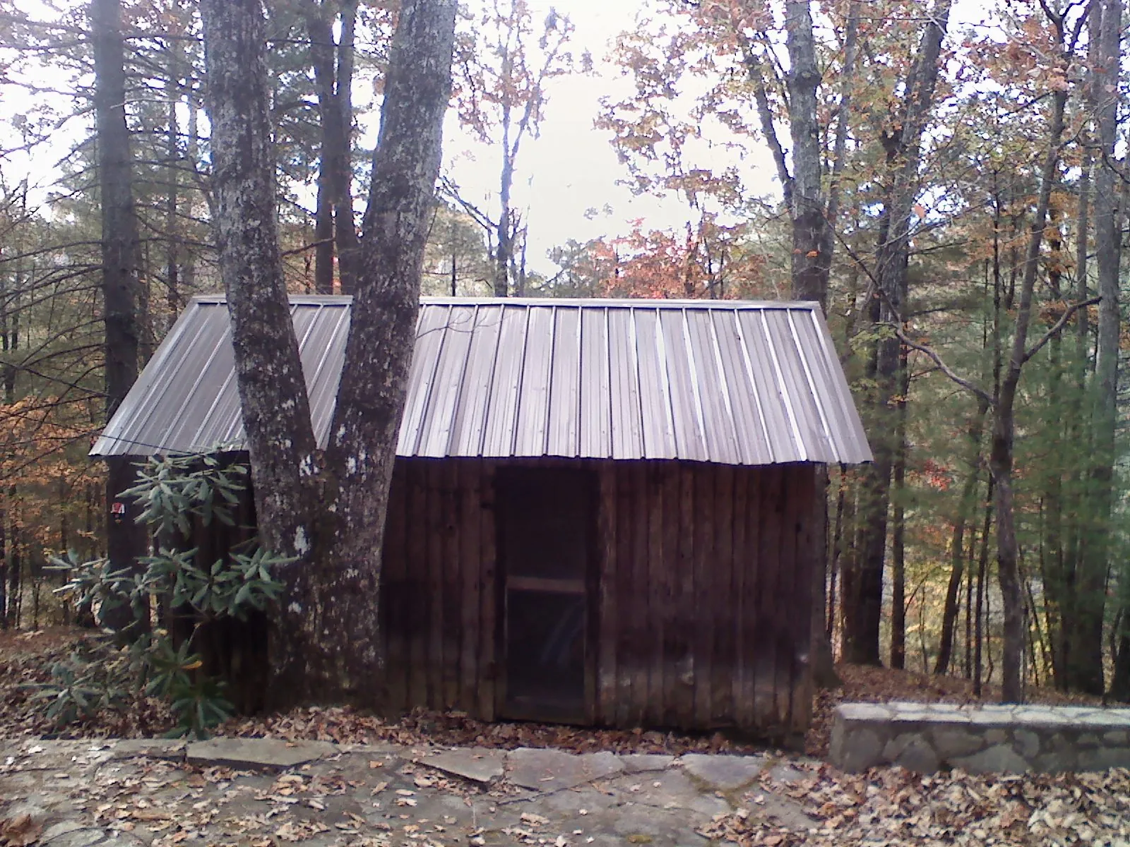 New metal gable roof on a small log shed among the trees in Kintnersville