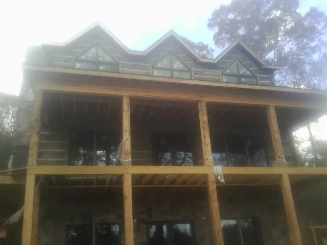 Dormers and porch framing on a large log home under construction — Roof Coating work by our crew in Kintnersville