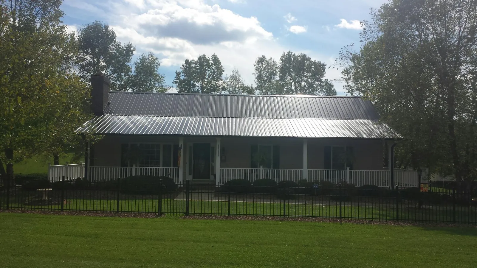 Gray metal roof on a brick ranch with a full width front porch — Gutter Guard Installation work by our crew in Kintnersville