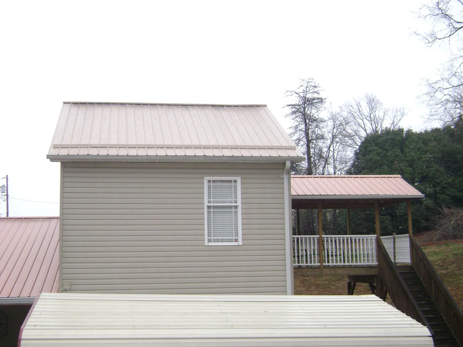 Tan metal roofs on a two story addition and attached porch, from a Roof Replacement job in Kintnersville