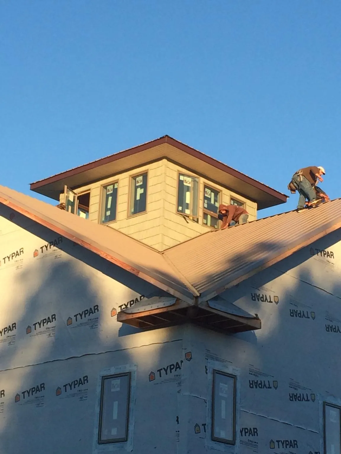 Roofers working around a rooftop cupola on a new metal roof at sunset — Roof Waterproofing in Kintnersville by Roofing Brothers